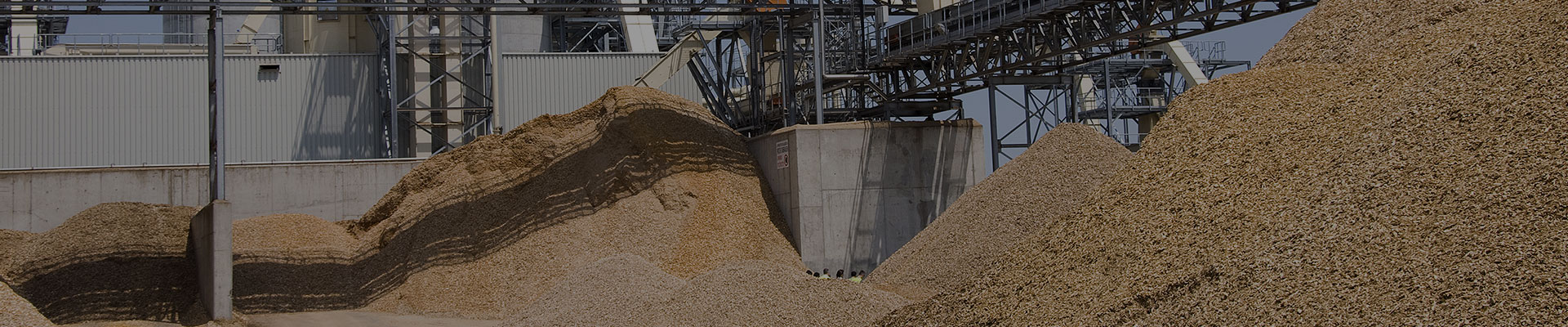 Wärmetauscher bei der Holzverarbeitenden Industrie in einer Halle mit Bergen aus Sägespähnen